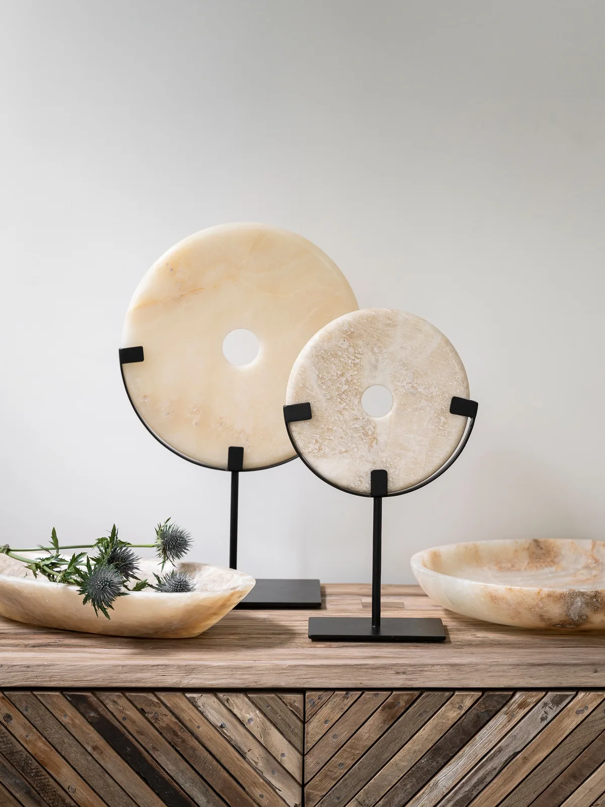 Zwei Geschirr Bean Dekoscheiben auf Ständern, mit zwei passenden Schalen und Disteln auf einem Holzsideboard - MUST Living