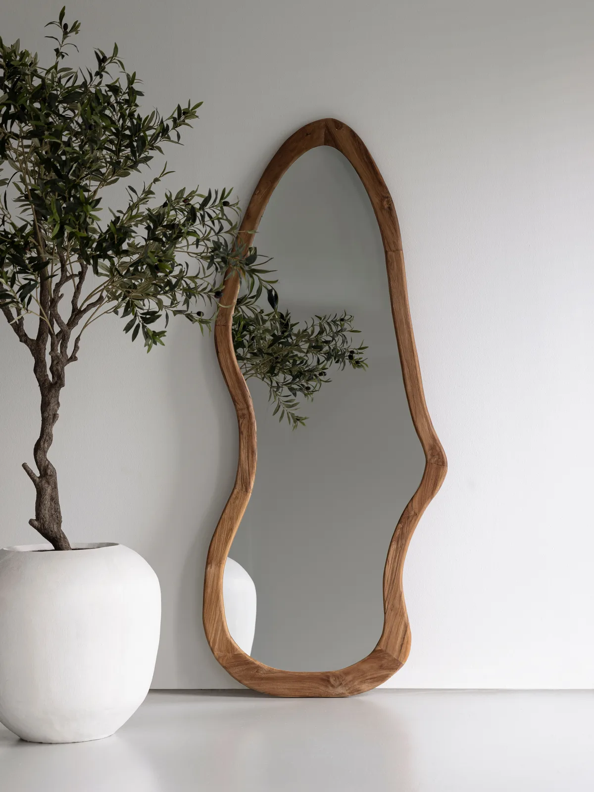 Spiegel Mirror Mateo mit organischem Holzrahmen lehnt an einer weißen Wand neben einer Pflanze - MUST Living