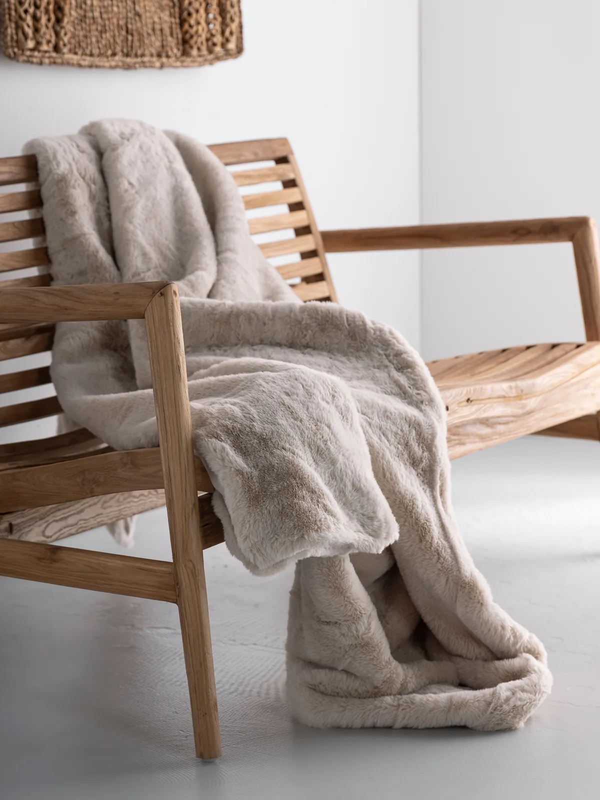 Kissen Plaid Lodge, eine weiche beigefarbene Decke, drapiert über eine Holzbank in einem hellen Studio - MUST Living