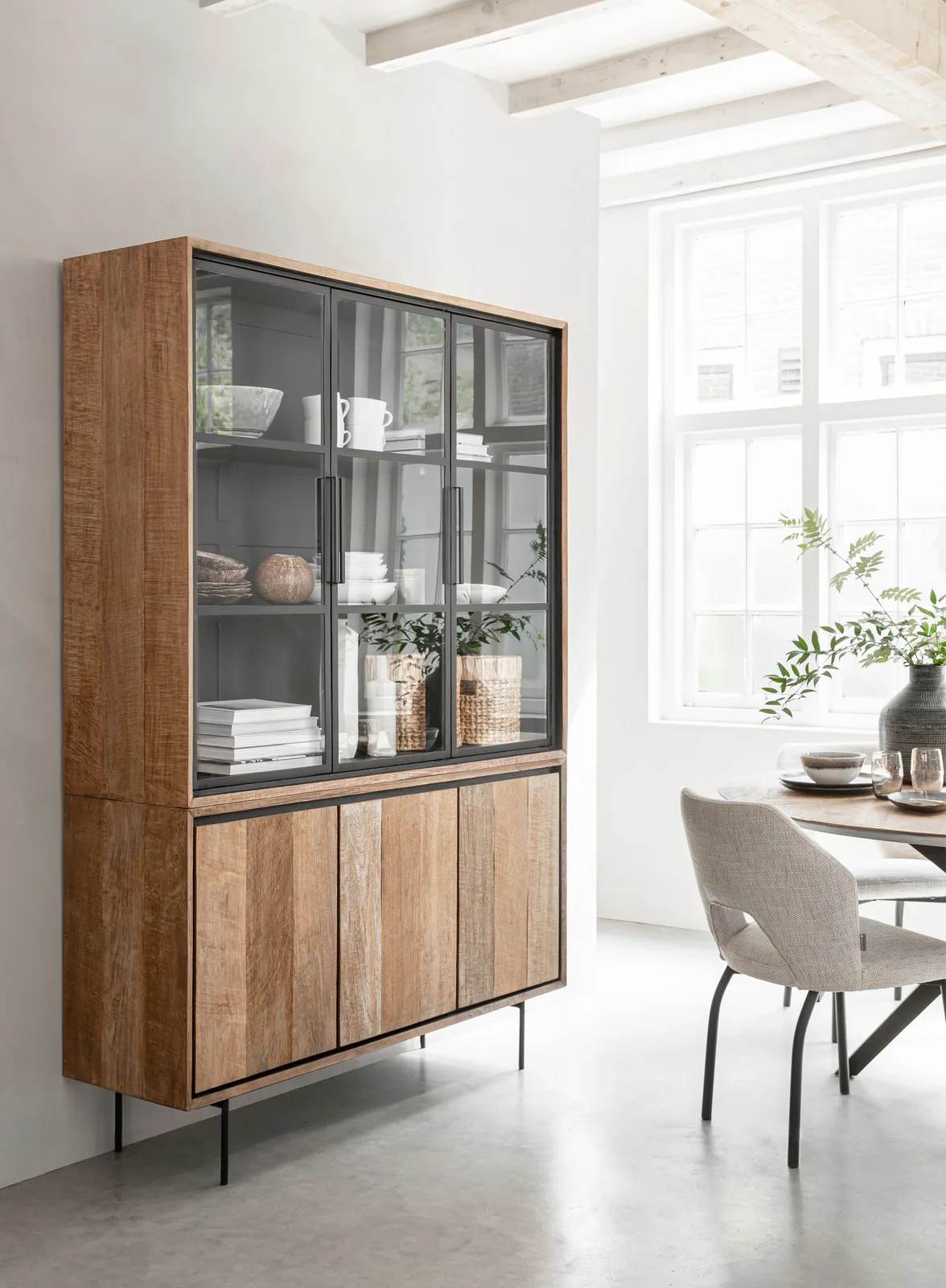 Vitrinekast Metropole in een lichte woonkamer met een eettafel en stoelen, vanuit een laag standpunt gefotografeerd - DTP Home