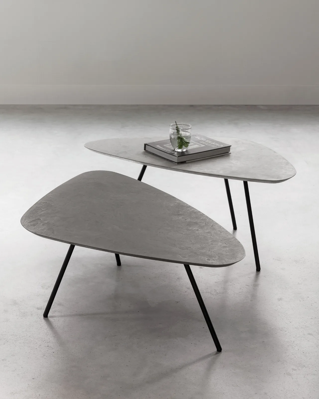 Twee Salontafels Plectro Air met organische vormen, de een iets hoger en met een boek en glas erop - DTP Home