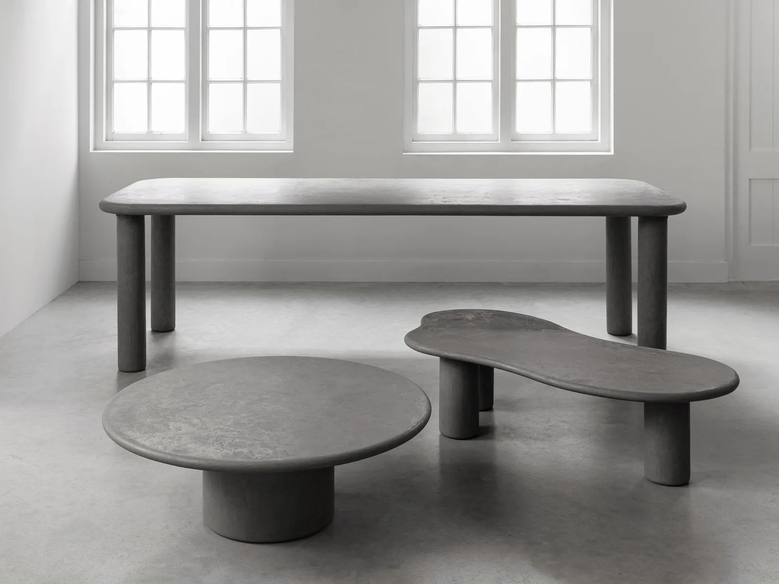 Der Esstisch Clio rund in einer Studio-Umgebung mit zwei Couchtischen, aus einer niedrigen Perspektive gesehen - DTP Home