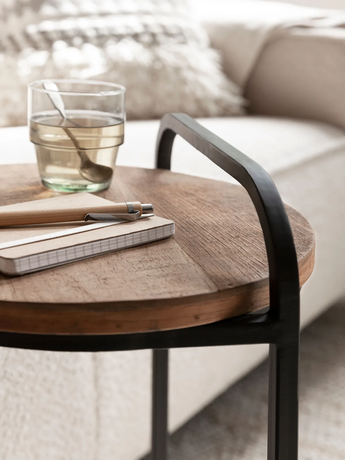 Detailopname van de Laptoptafel Soho met een notitieboekje, pen en glas op het houten blad, vanuit een laag standpunt - DTP Home