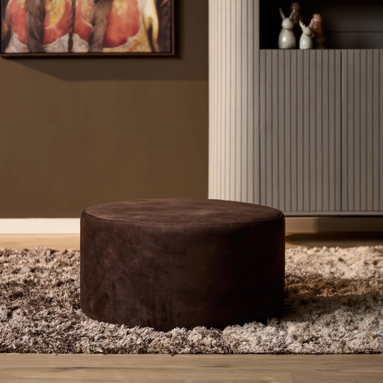 MySofa Runder Hocker auf einem zotteligen Teppich in einem modernen Interieur mit Kunst an der Wand