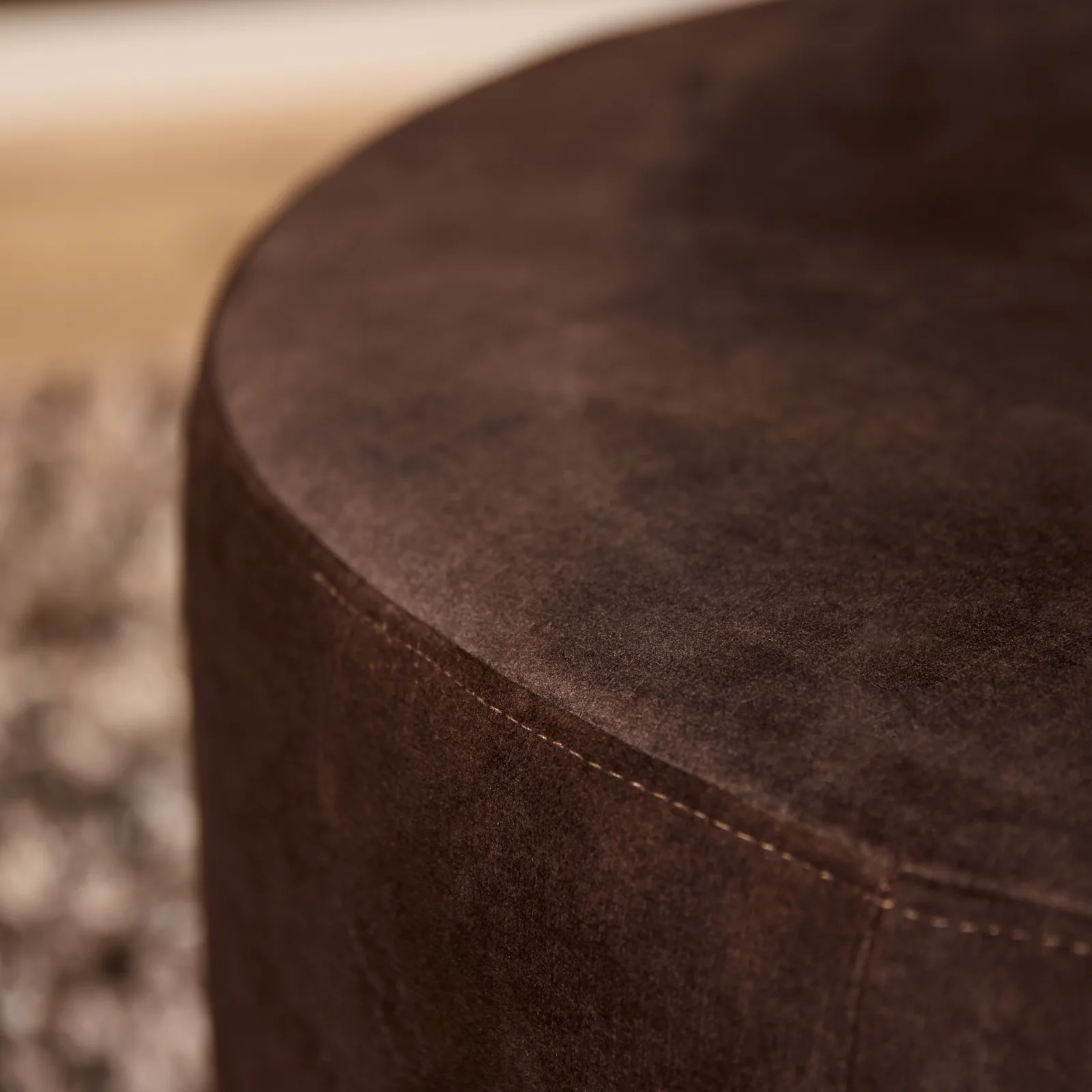 Nahaufnahme des braunen MySofa Runder Hocker, mit Fokus auf den Stoff und die Nähte an der Seite