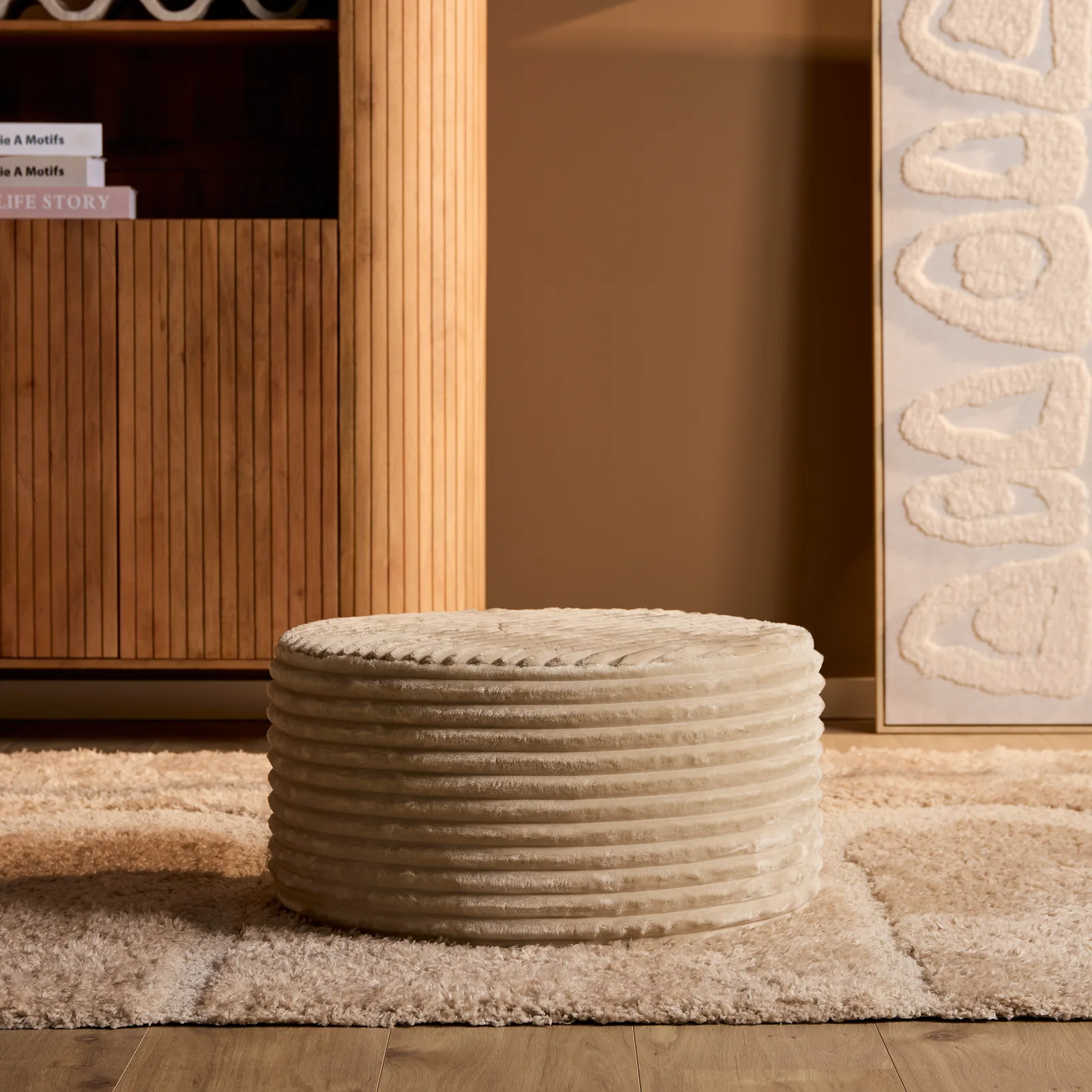 MySofa Runder Hocker in einem stimmungsvollen Wohnzimmerambiente mit einem Holzschrank und einem cremefarbenen Teppich