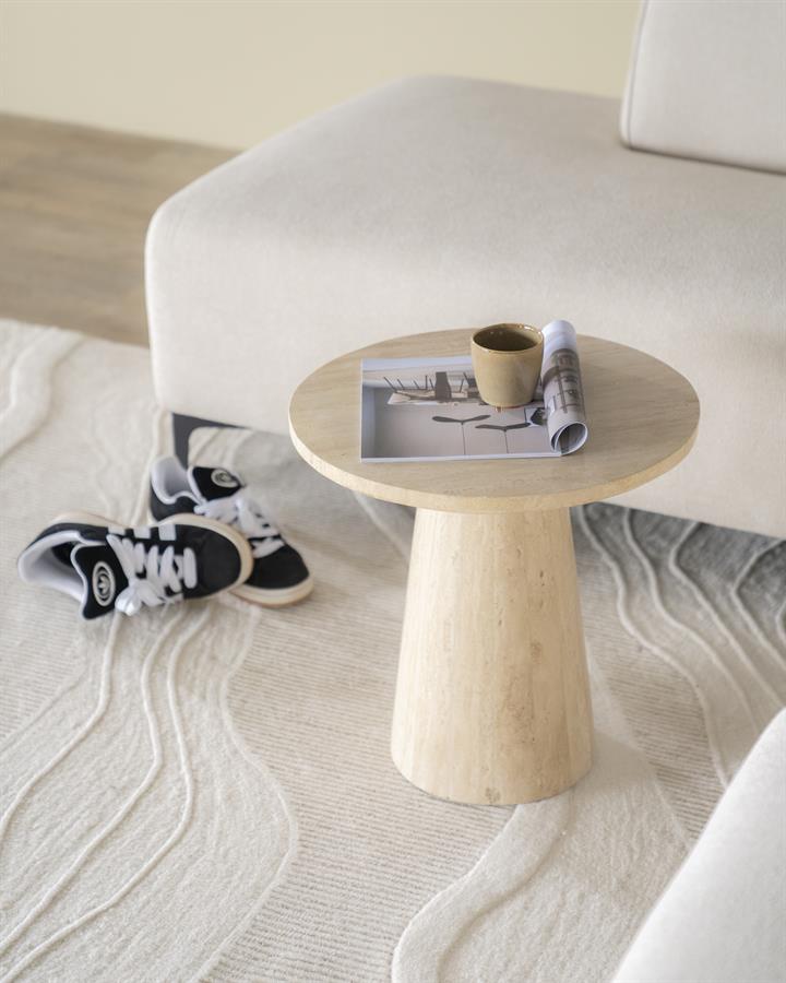 Beistelltisch Aime aus Travertin in einem hellen Wohnzimmer mit einer Zeitschrift und einer Tasse darauf - Eleonora