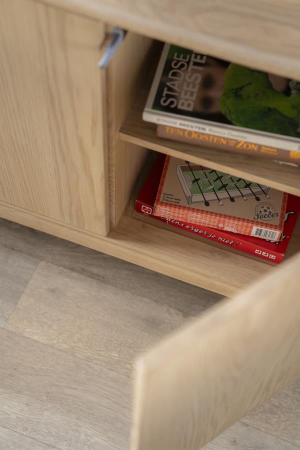 Nahaufnahme des Sideboard Harvey mit teilweise geöffneter Tür, Büchern und einem Spiel im Fach - Eleonora