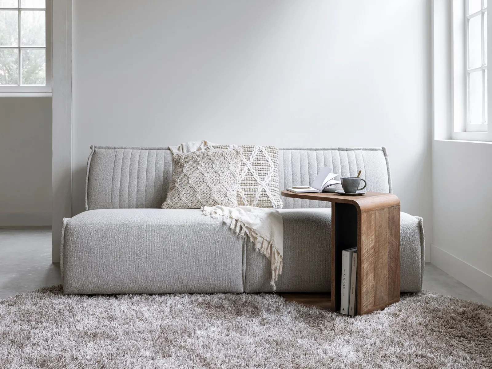 De Laptoptafel Evo in een lichte woonkamer met een grijze bank, kussen en vloerkleed - DTP Home