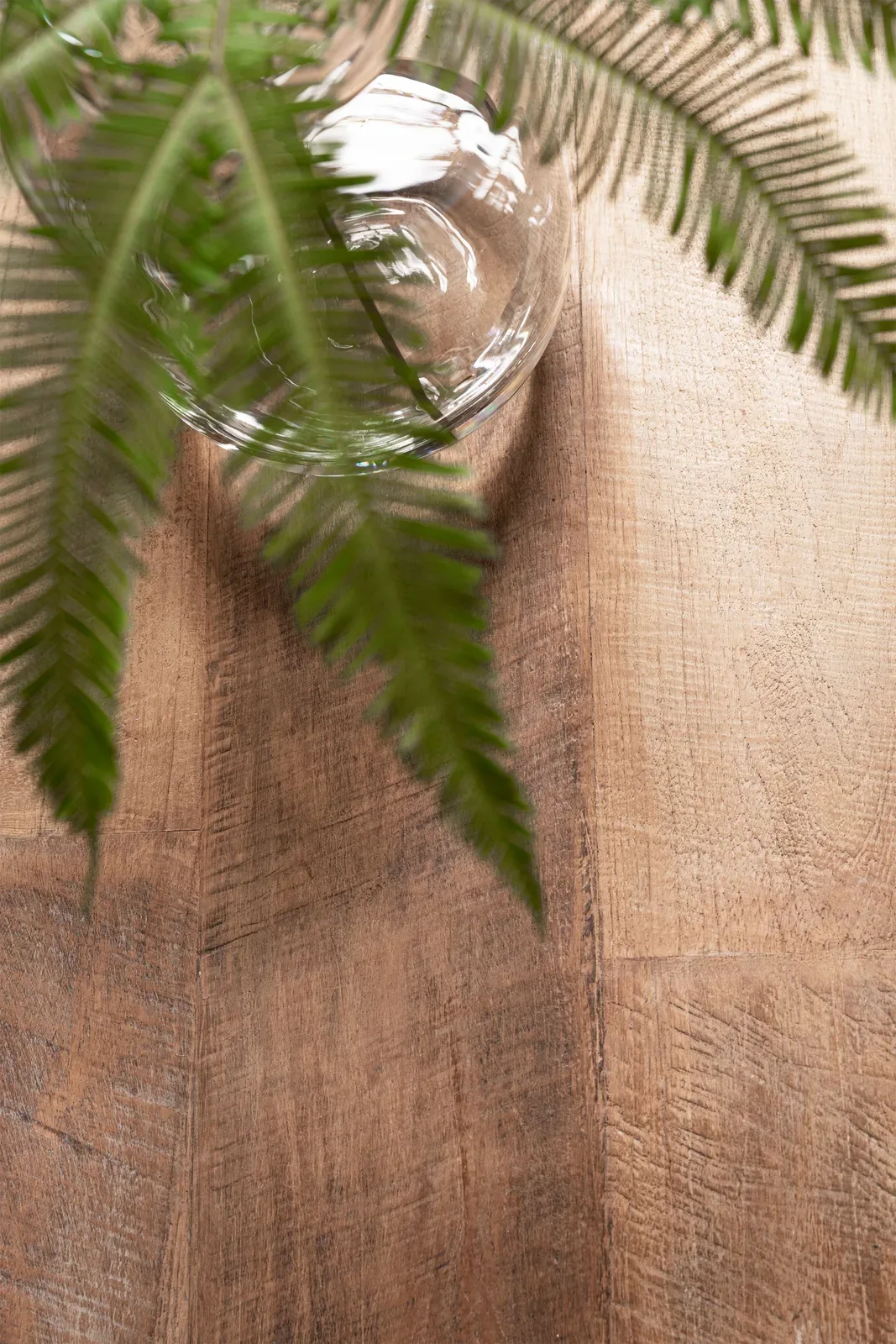Detail van een glazen vaas met groene planten op een houten vloer - DTP Home