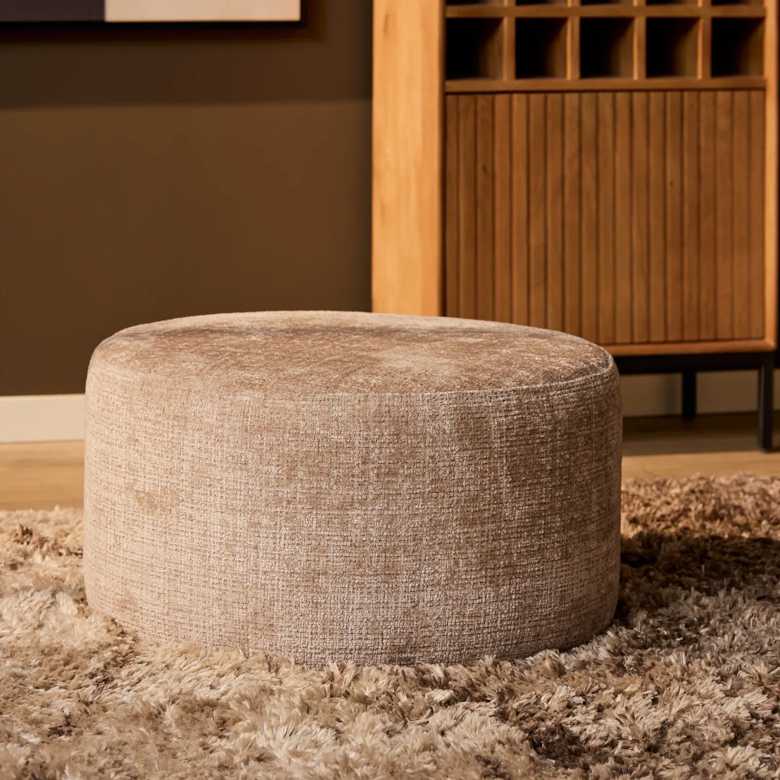 MySofa Runder Hocker in einem Wohnzimmer mit braunem Teppich und Holzschrank