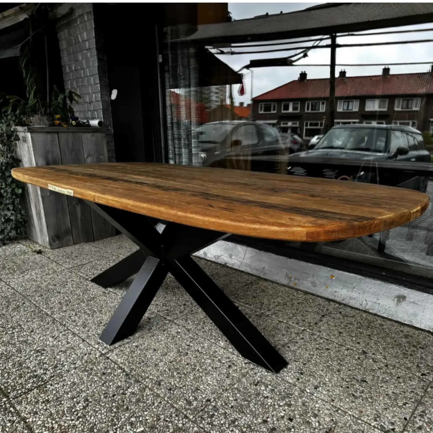 Eettafel Donny teakhout Deens Ovaal met zwart metalen onderstel, staand op een terras - World of Brosi