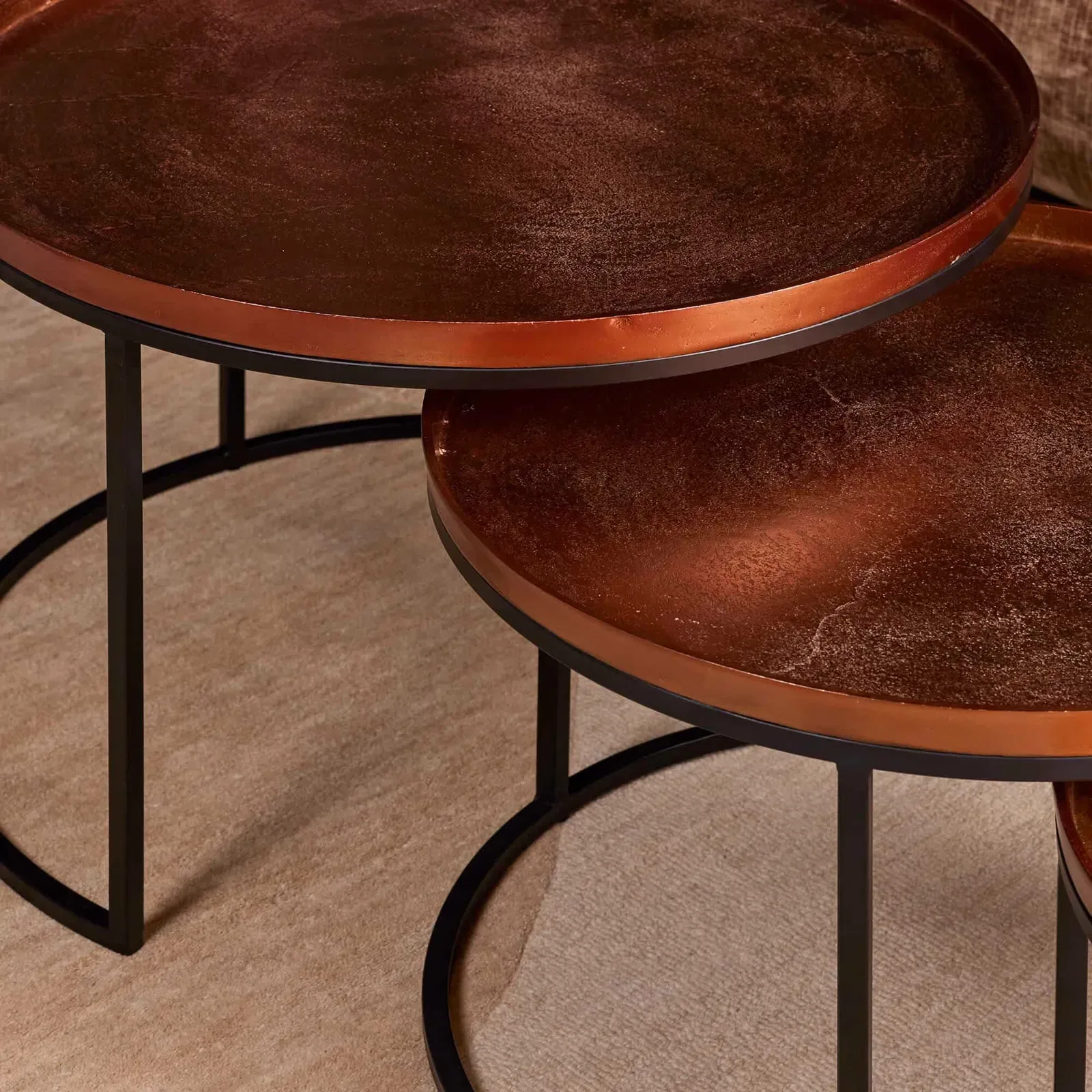 Detail des Couchtisch Clive, 3er-Set, mit runden kupferfarbenen Platten und schwarzen Beinen auf einem Teppich - Starfurn