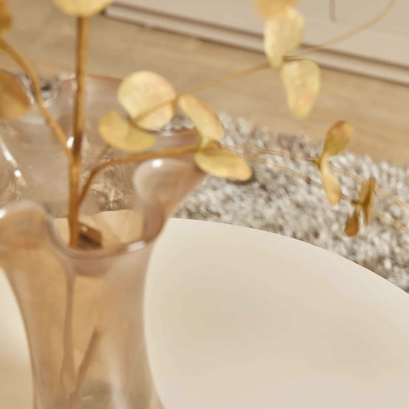 Detailaufnahme des Couchtisch Bellis, mit einer Vase mit Ästen auf dem Tisch und einem Teppich im Hintergrund - Starfurn