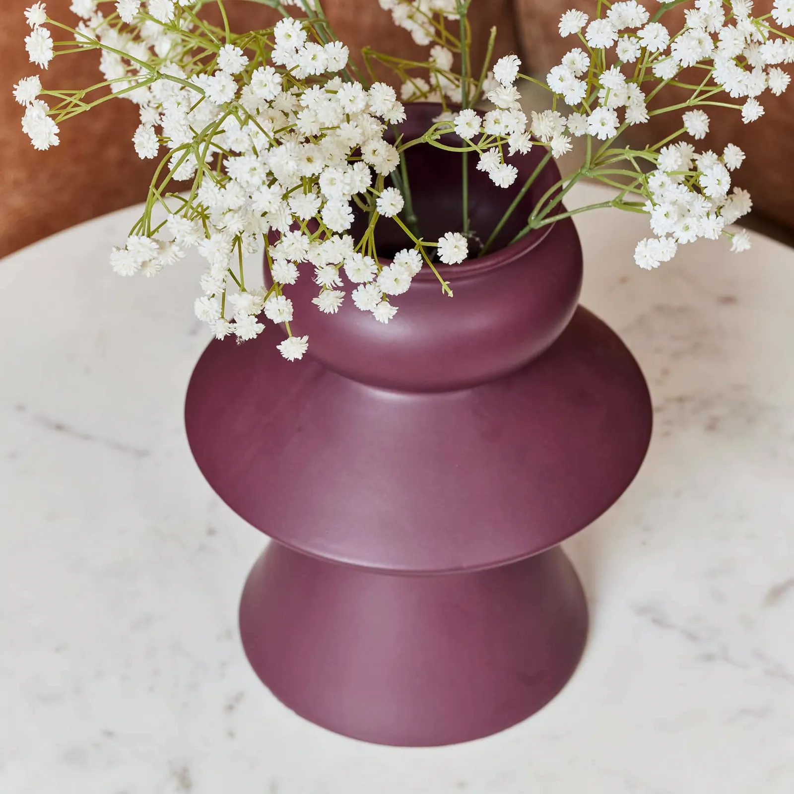 Detail van een paarse vaas met witte bloemen op een witte marmeren salontafel Nova - Starfurn