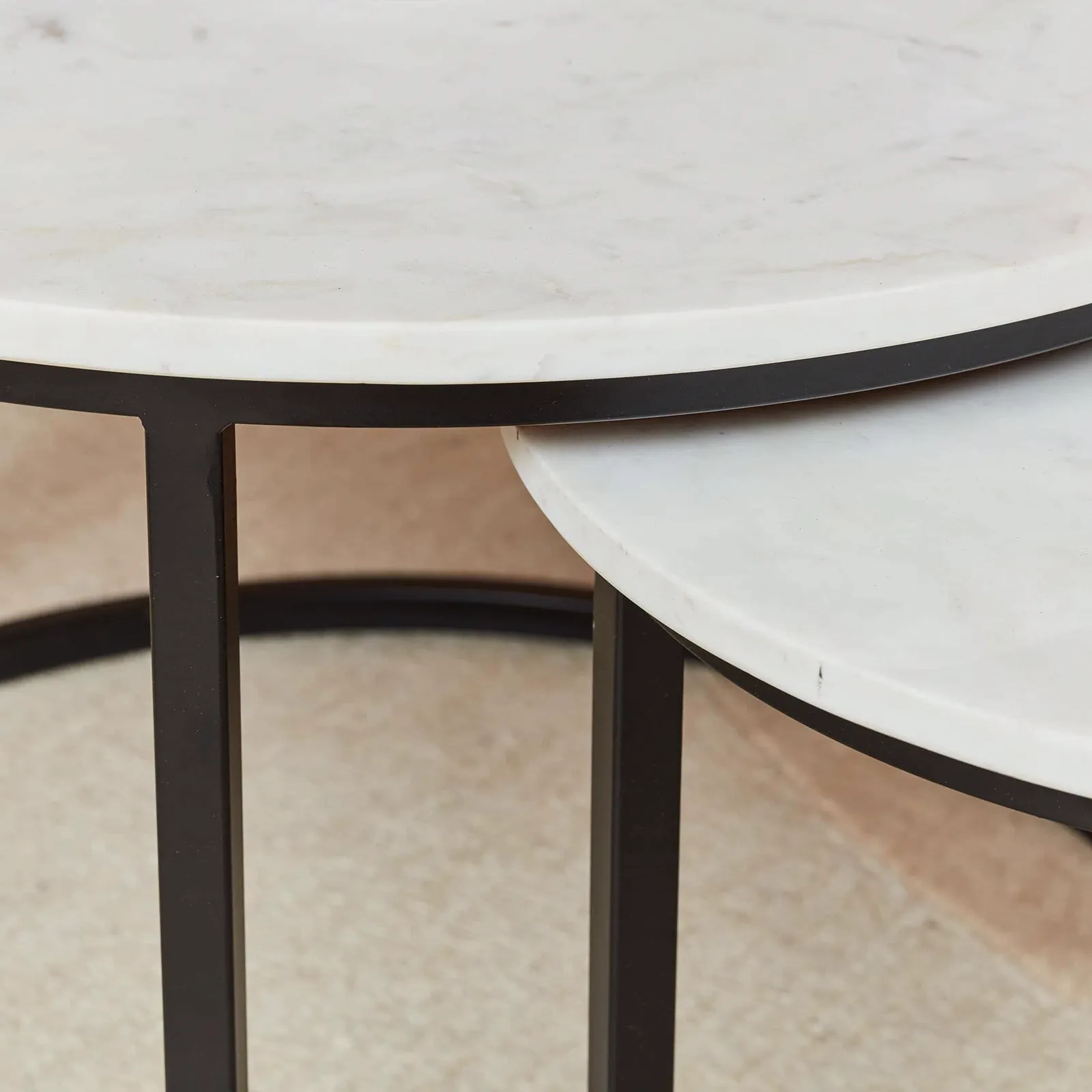 Detailopname van de ronde witte marmeren bladen en zwarte metalen poten van de Salontafel Nova White marble - Starfurn