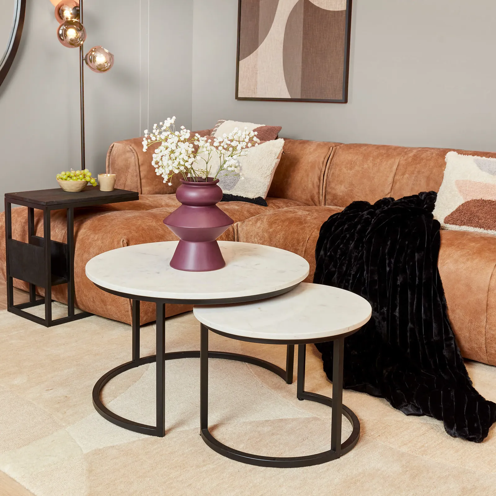 Set van 2 ronde Salontafel Nova White marble, staand voor een bruine bank in een woonkamer - Starfurn