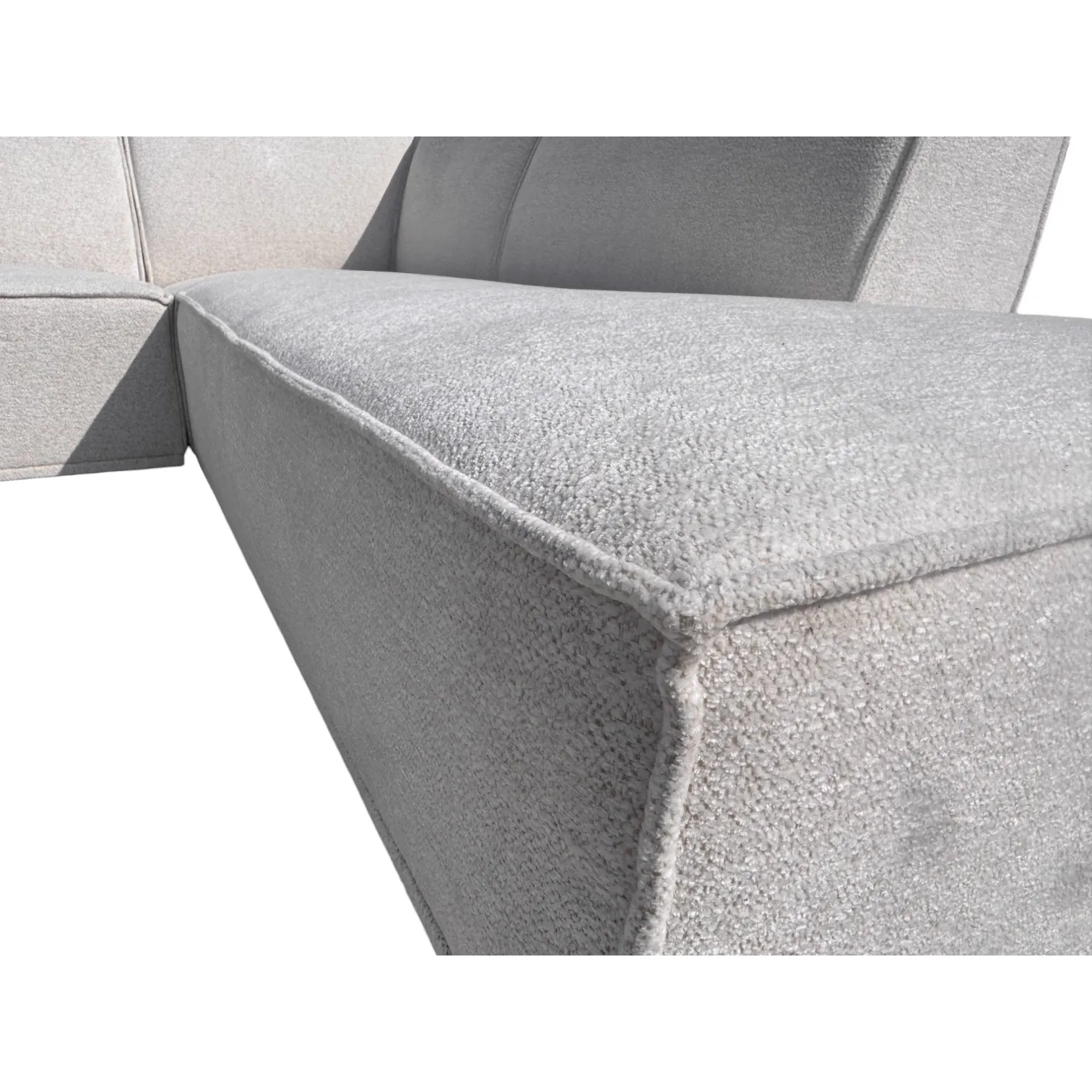 Detailaufnahme des Ecksofas Charly, mit Fokus auf die Textur des hellgrauen Stoffes und die Nähte - Sofa Industries