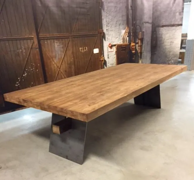 De Eettafel Jaxx teakhout, een lange houten tafel met metalen poten, in een industriële setting - B&B Collections