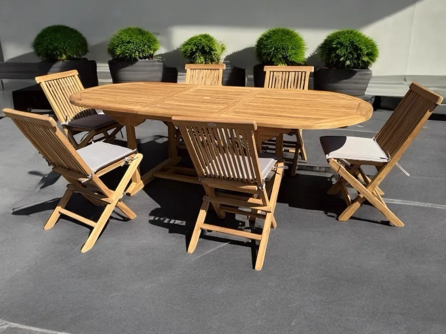Ausziehbarer Esstisch Teak mit 6 Stühlen auf einer Terrasse mit grünen Pflanzen im Hintergrund - Mokana Furniture