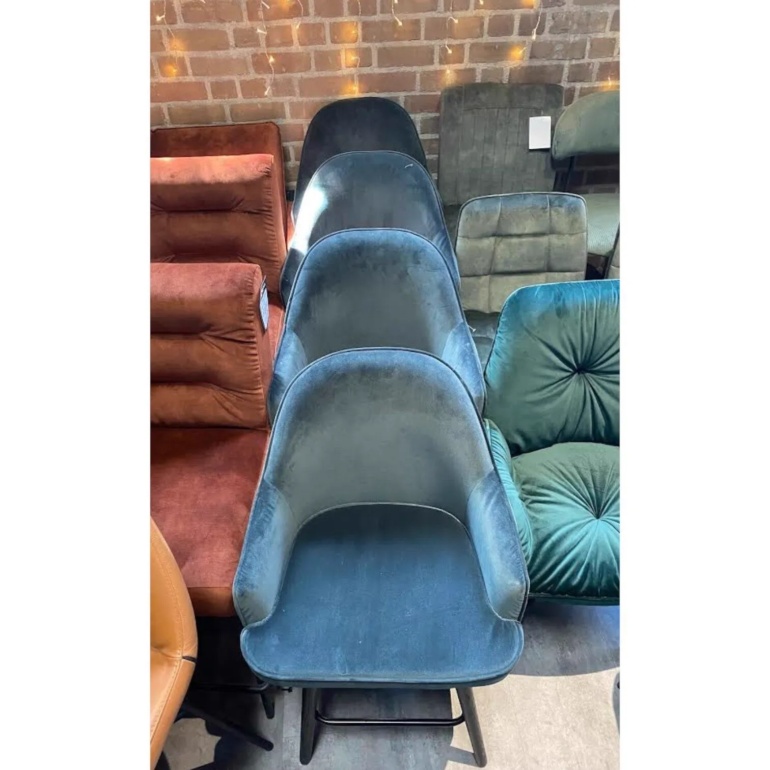 Barhocker Blue Set von 4 und andere Stühle in verschiedenen Farben in einer Reihe, mit einer Ziegelwand im Hintergrund