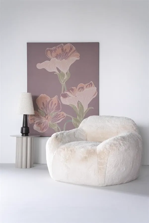 Der beige Hug Sessel in einem modernen Studio mit Blumenkunstwerk und einem Beistelltisch mit Lampe - By-Boo