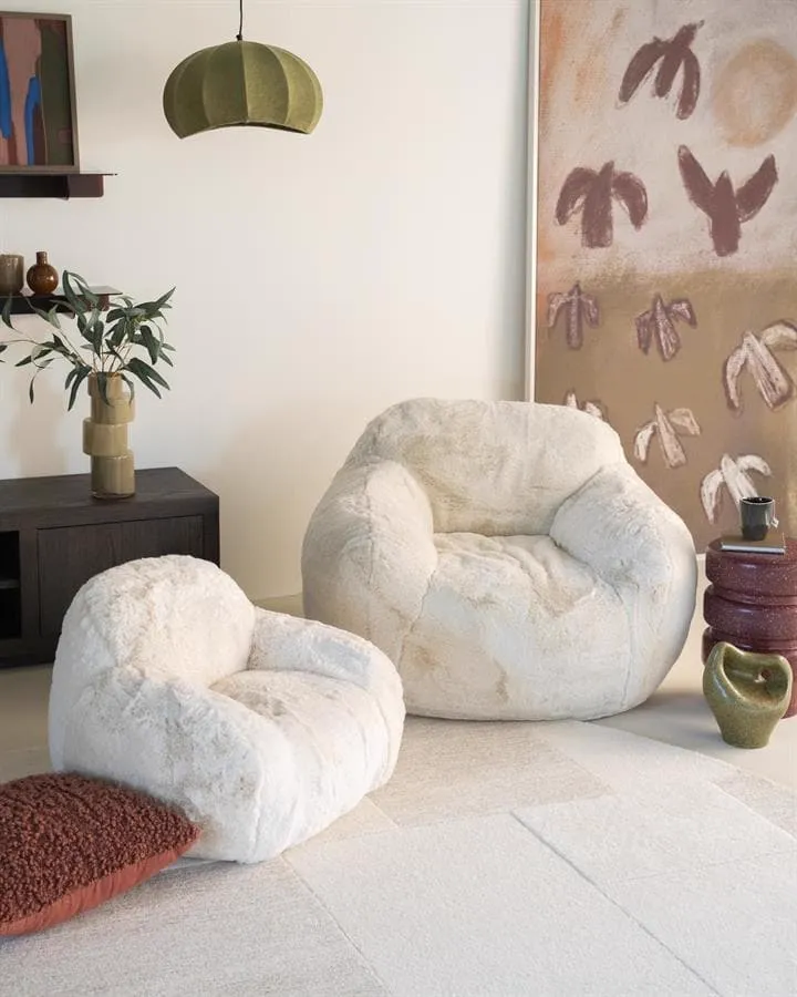 Zwei beige Hug Sessel von By-Boo in einem stimmungsvollen Wohnzimmer mit Kunst und Pflanzen