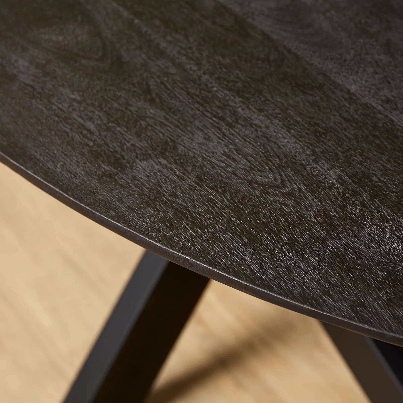 Nahaufnahme der dunklen Tischplatte des Esstisch Brandy Black, mit sichtbarer Holzmaserung und einem schwarzen Tischbein - Starfurn