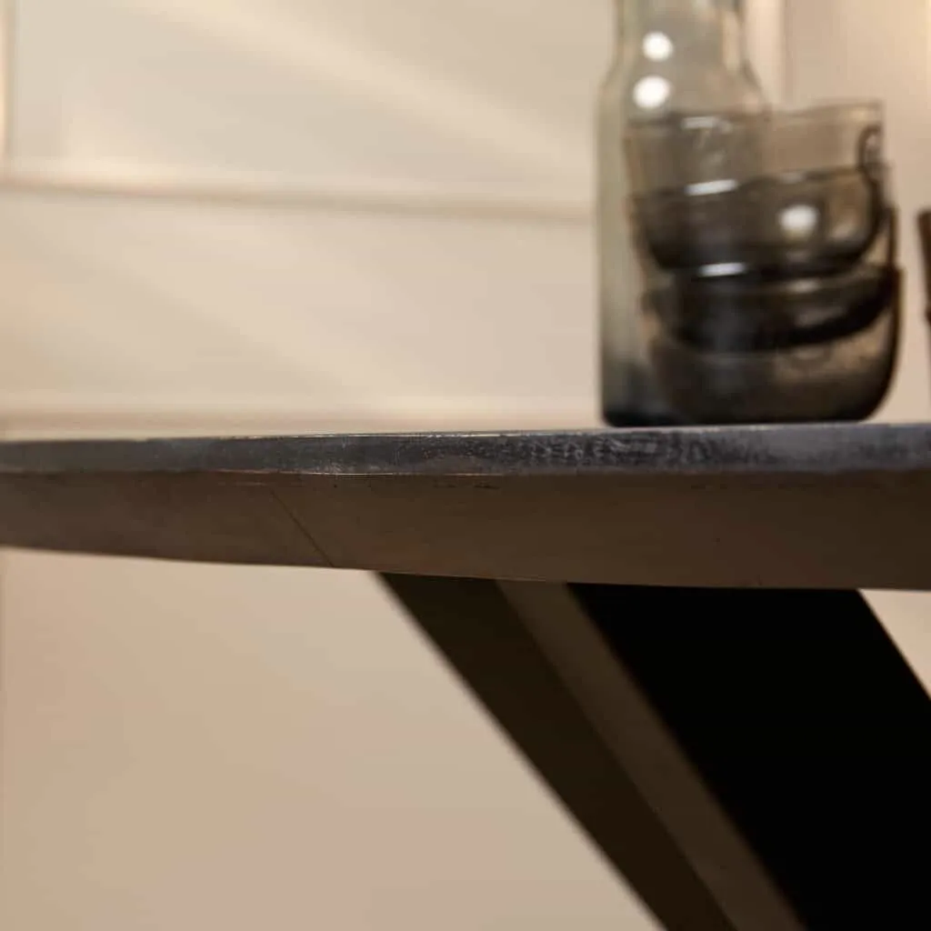 Nahaufnahme des Esstisch Brandy Black, mit einem Detail der Kante der ovalen Tischplatte und der Tischbeine - Starfurn