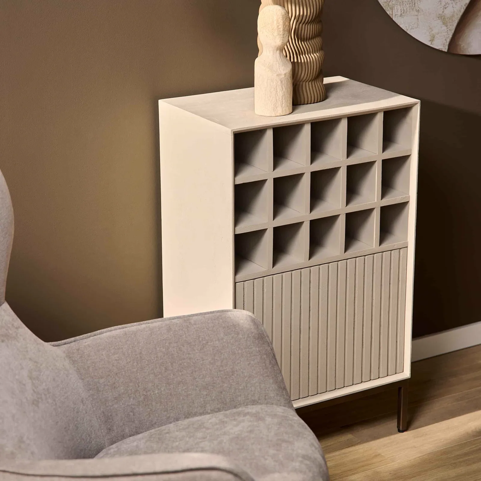 Weinschrank Madison Sand, 55 cm, in einem modernen Interieur mit einem grauen Sessel und brauner Wand - Starfurn