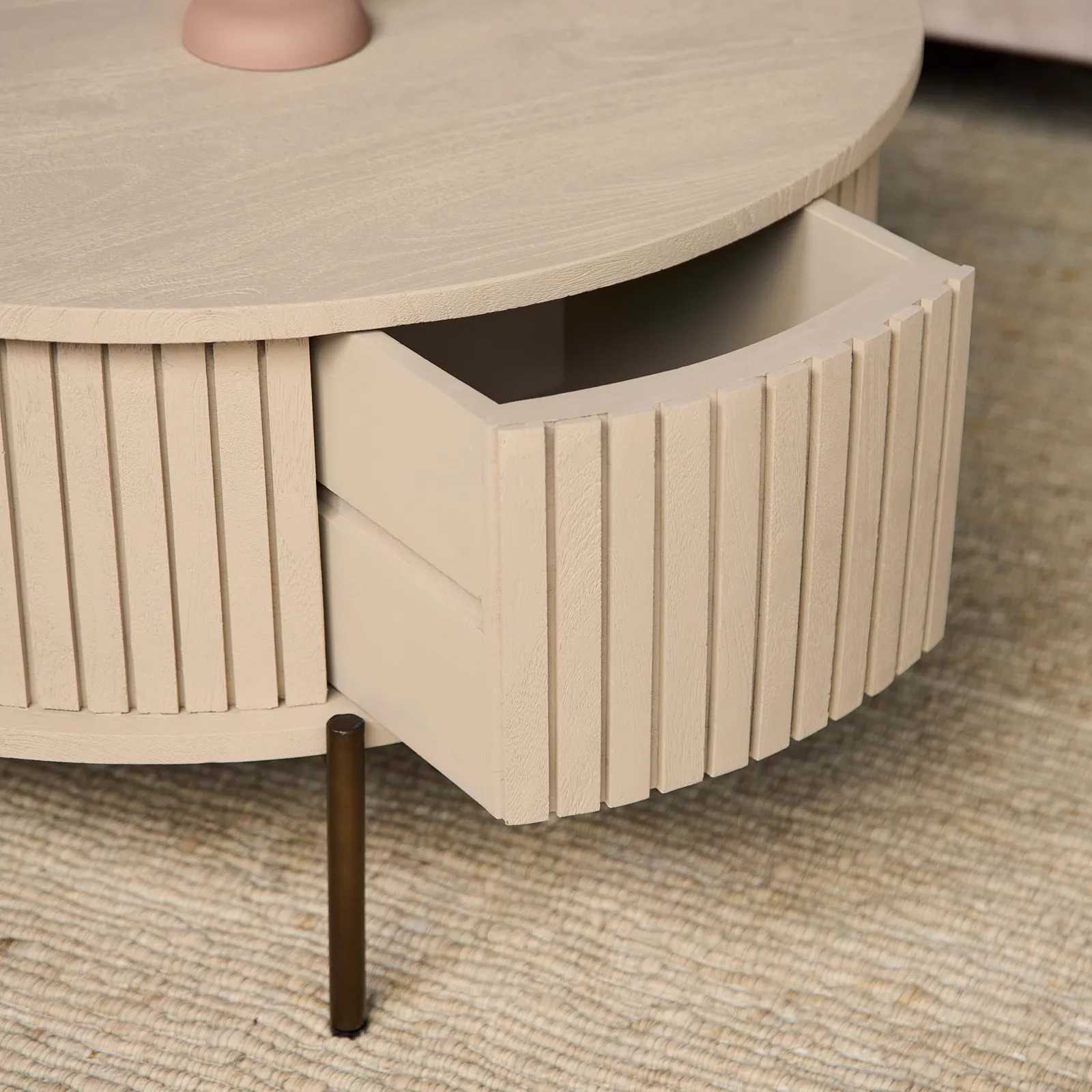 Detail des Couchtischs Madison Sand, mit einer offenen Schublade und einem Bein auf einem Teppich - Starfurn