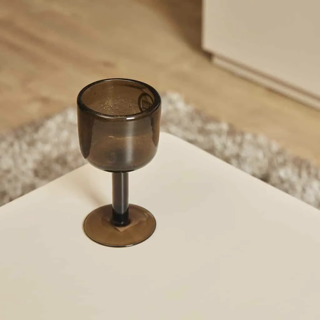 Eine Nahaufnahme eines Couchtischs Saya mit einem dunklen Weinglas aus Glas, aus einer hohen Perspektive - Starfurn