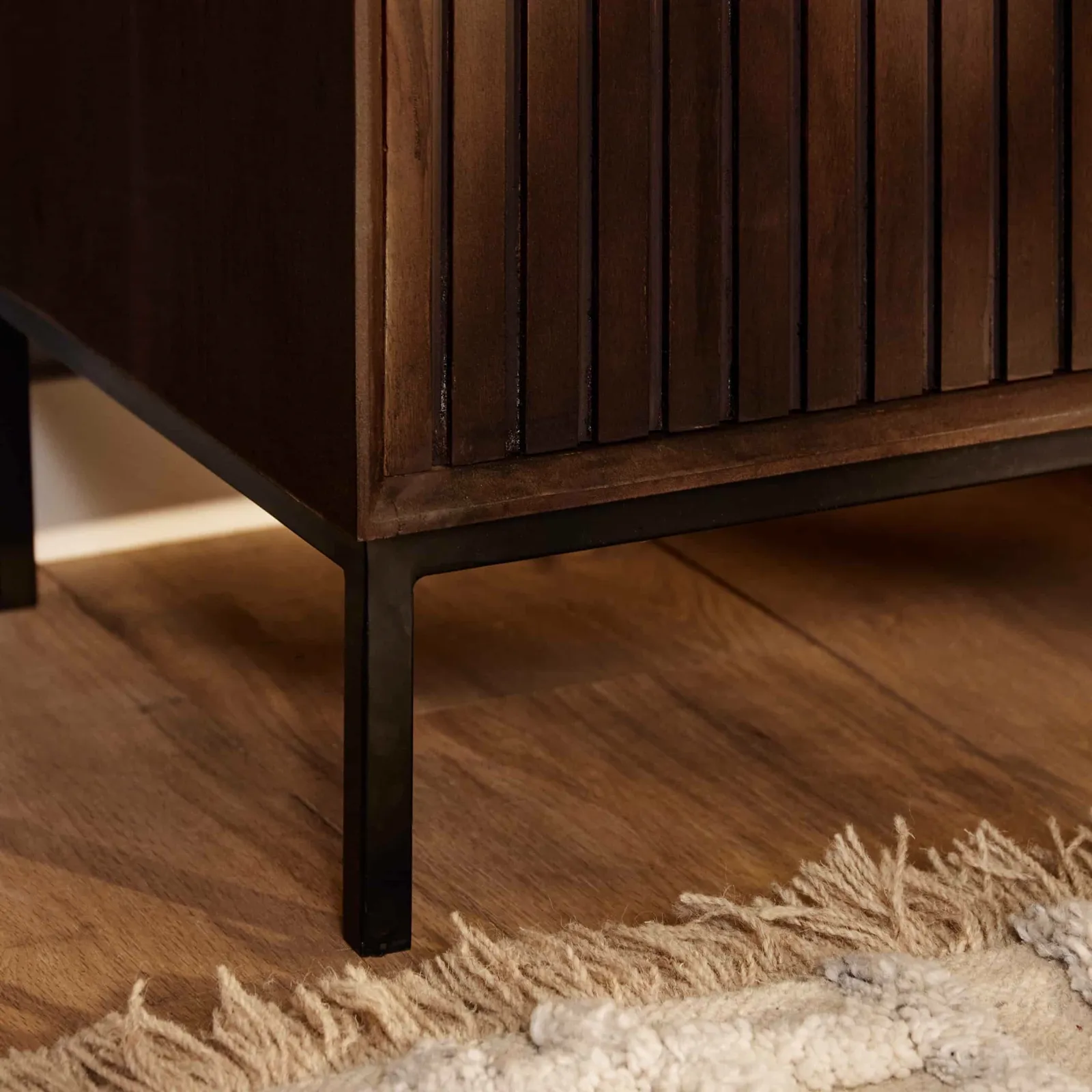 Detailansicht des dunkelbraunen Holzschranks des Tv-Schrank Madison Brown mit schwarzen Metallbeinen auf einem Holzboden - Starfurn