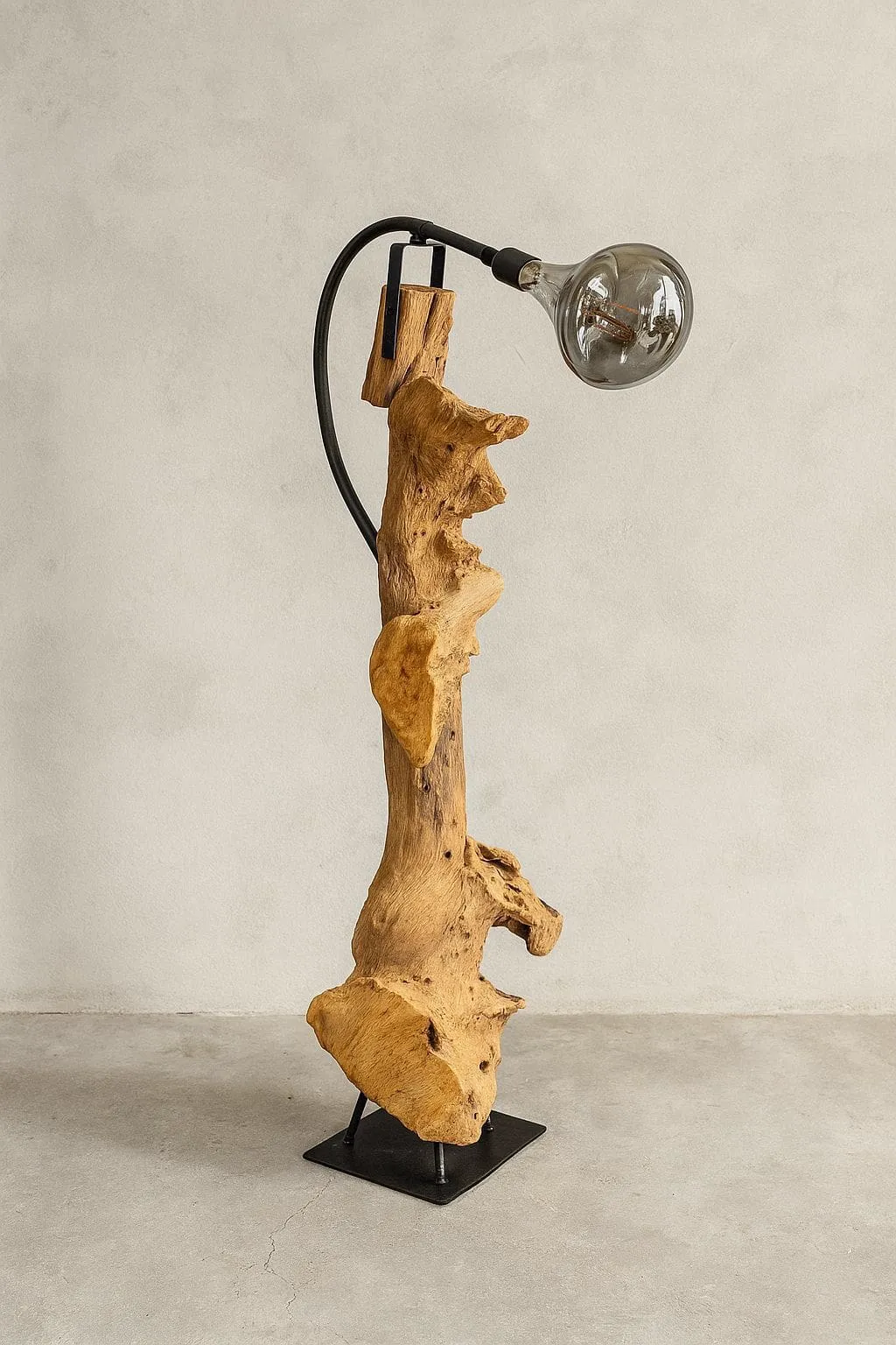 Stehleuchte Svena aus Teakholz mit einer Glühbirne, stehend auf einem schwarzen Metallsockel in einem Studio - World of Brosi