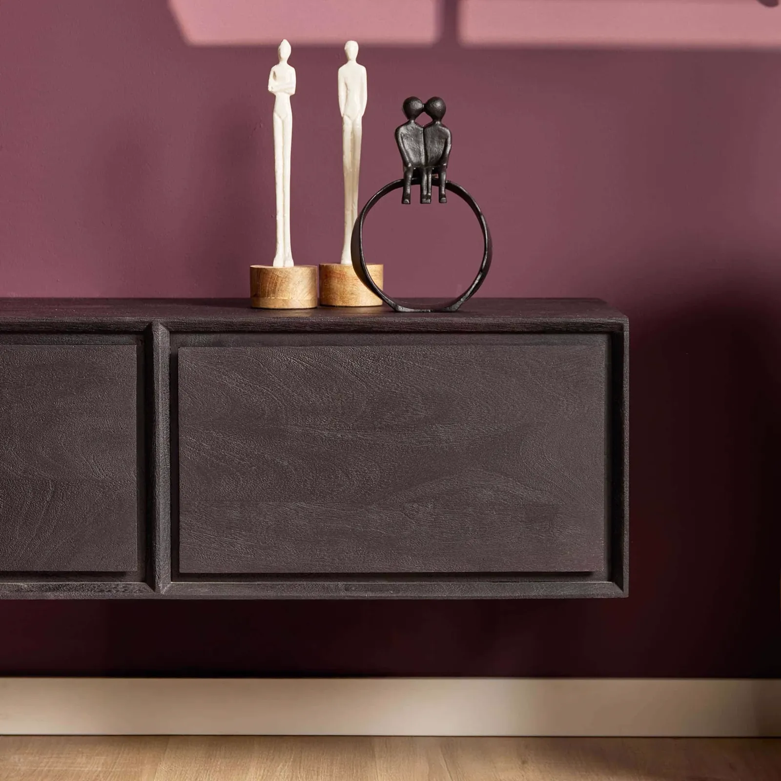 Schwebendes TV-Möbel Ambiance Black, mit zwei weißen und einer schwarzen Dekofigur darauf, vor einer lila Wand - Starfurn