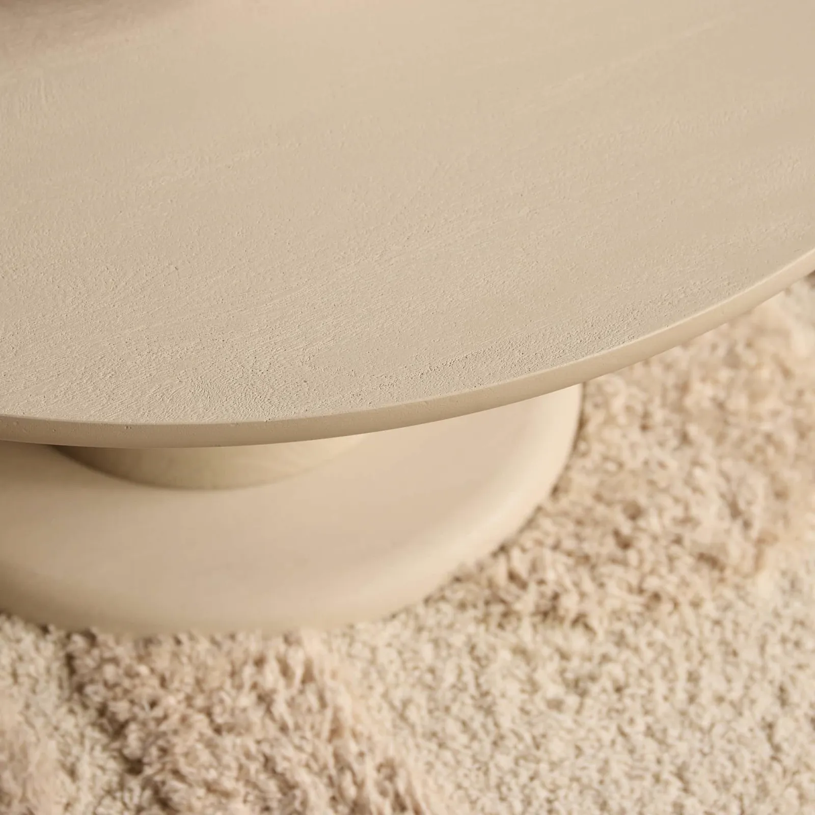 Detailaufnahme des Couchtischs Mabel, mit einer Nahaufnahme der runden Tischplatte und des Fußes auf einem hellen Teppich - Starfurn