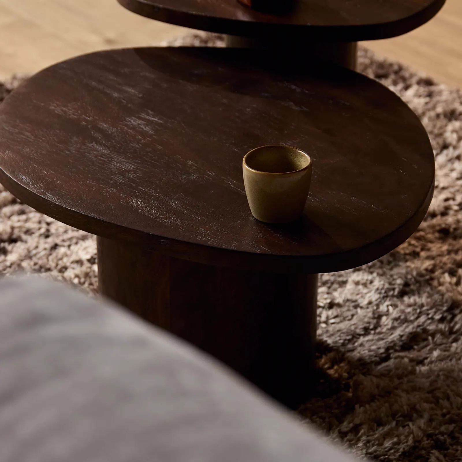 Detail des Couchtischs Mirre in Braun, mit einer kleinen Tasse darauf, von der Seite gesehen - Starfurn