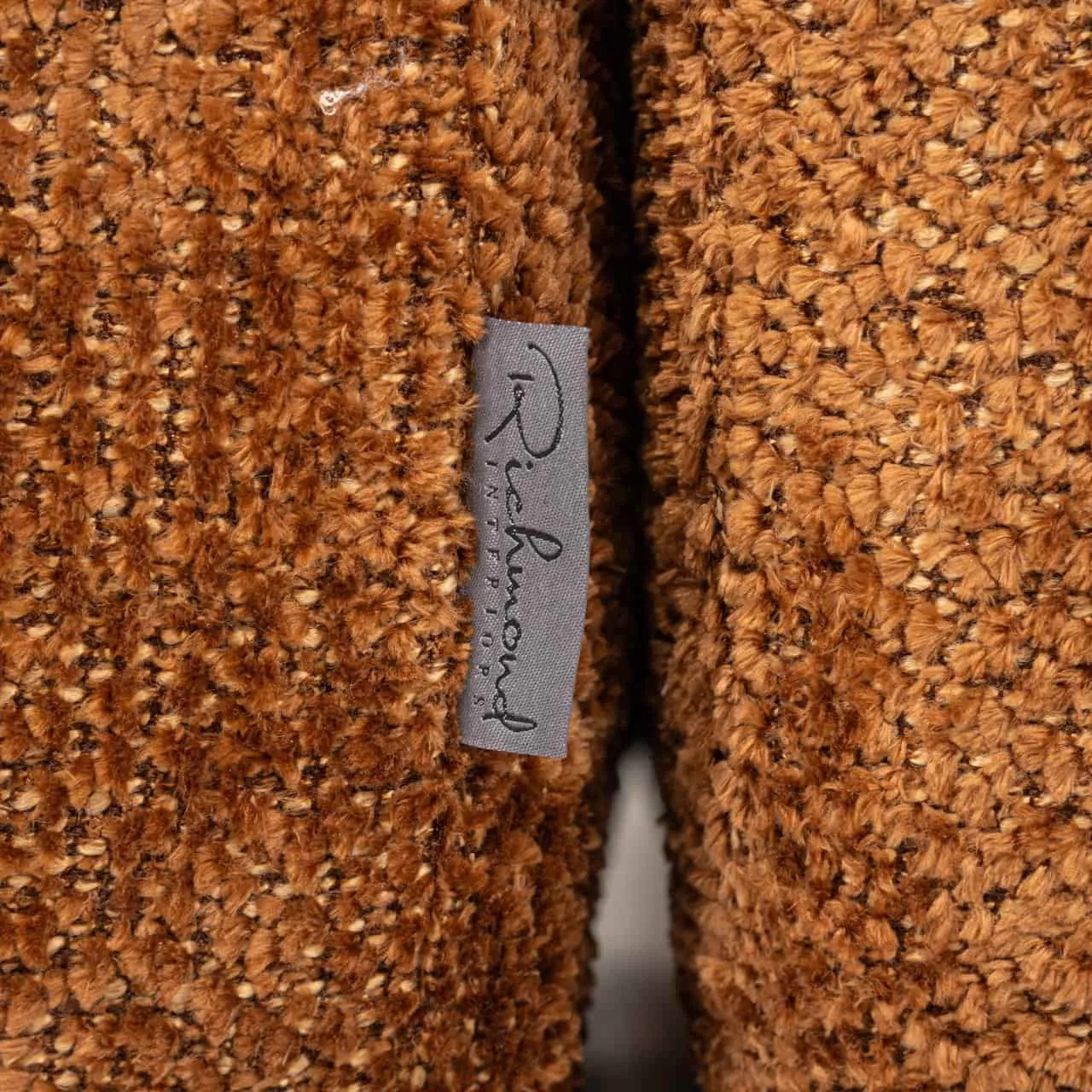Nahaufnahme des weichen, braunen Stoffes des Sofas Cube lovely cinnamon mit einem Richmond Interiors Etikett