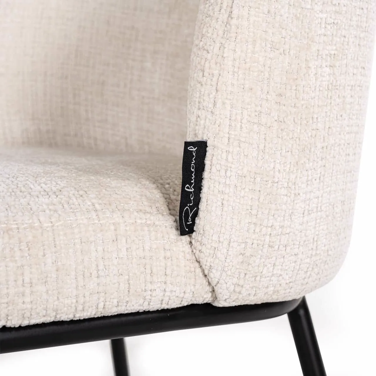 Nahaufnahme des beigefarbenen Stoffes und des schwarzen Markenetiketts des Esszimmerstuhls Elvi Niagara Beige Brandverzögernd - Richmond Interiors