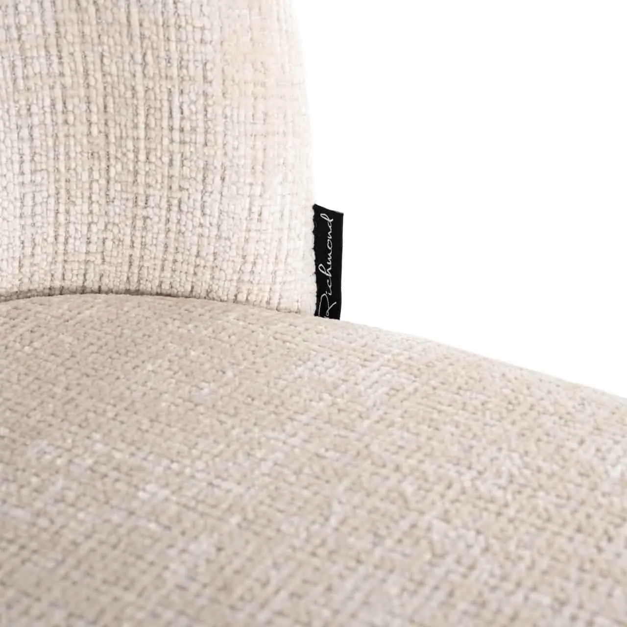 Detail des Esszimmerstuhls Elvi Niagara Beige, mit einer Nahaufnahme des beigen Stoffes und dem Richmond Interiors Etikett