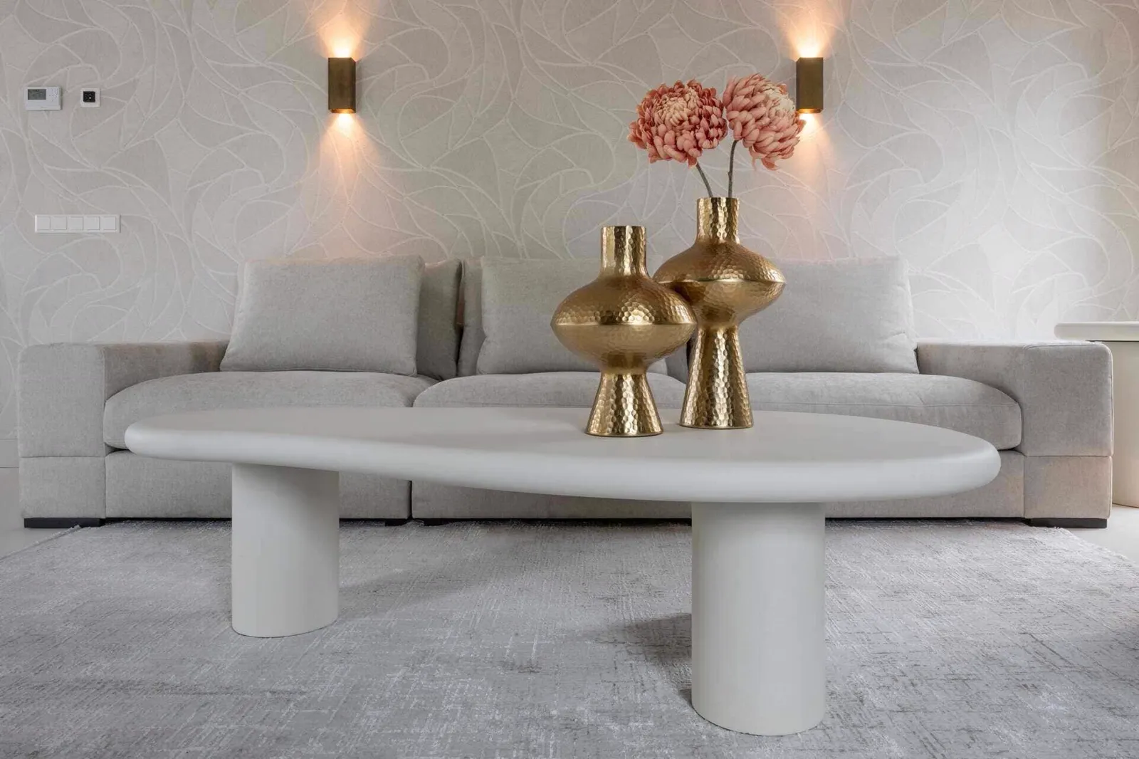 Der Couchtisch Bloomstone white 160x80 steht im Mittelpunkt eines hellen Wohnzimmers mit grauem Sofa und goldenen Vasen - Richmond Interiors
