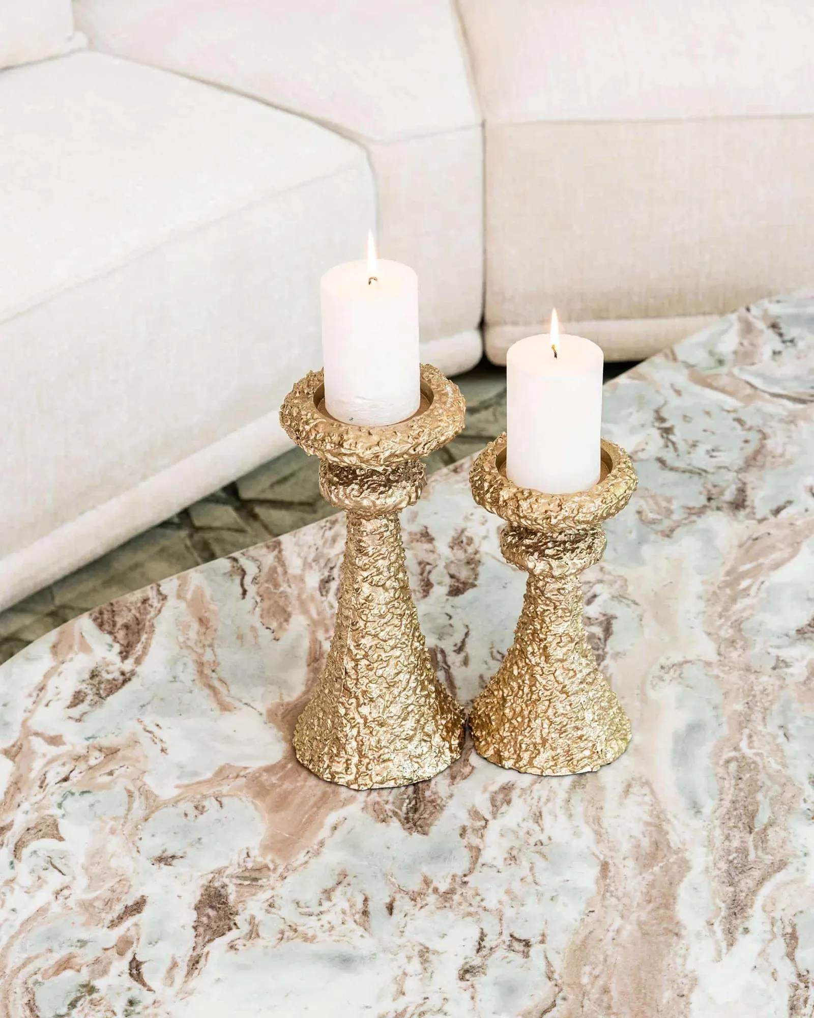 Couchtisch Coronel Blush beige mit zwei goldenen Kerzenständern und brennenden Kerzen, aus der Vogelperspektive - Richmond Interiors