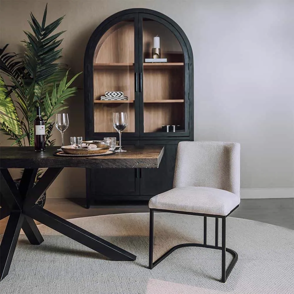 De Archi Stoel - fabric Eden 3 cream staat aan een houten eettafel in een sfeervolle eetkamer - Tower Living