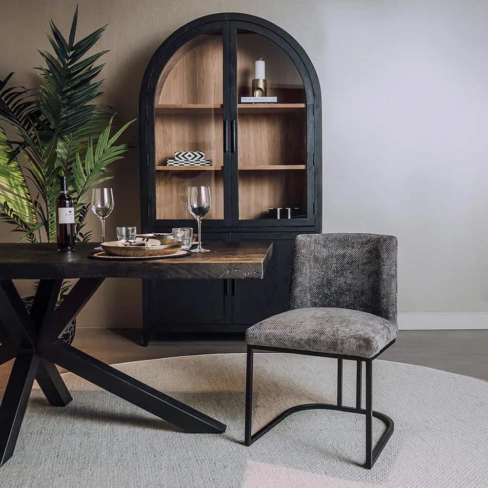 De Archi Stoel - fabric Eden 20 graphite in een sfeervolle eetkamer naast een houten tafel en een zwart dressoir - Tower Living