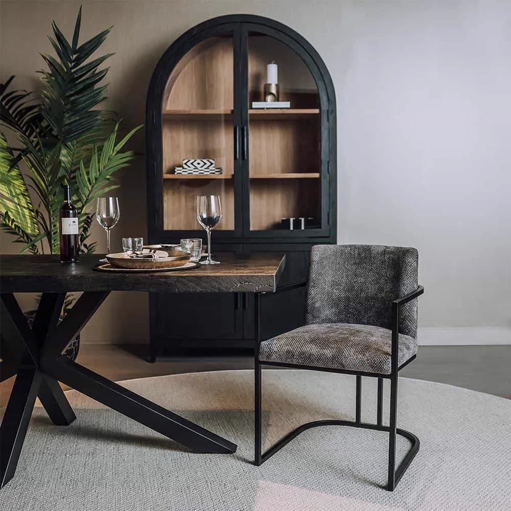 De Archi Armstoel - fabric Eden 20 graphite staat aan een eettafel in een sfeervolle woonkamer - Tower Living