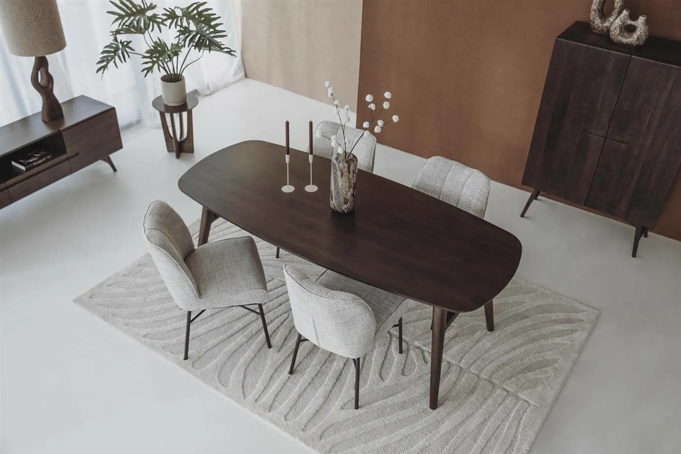 De Barzio Stoel - Oasis 91 Bisque in een interieur, van bovenaf gezien aan een donkere eettafel op een vloerkleed - Tower Living