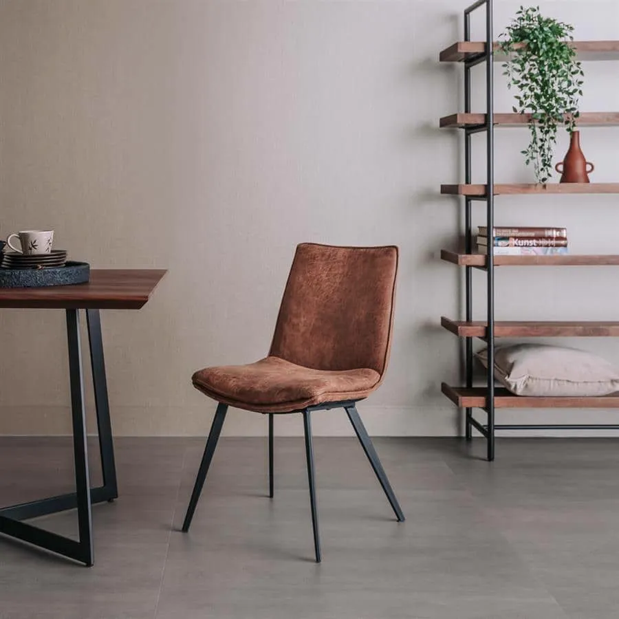 De Pamplona stoel in cognac stof staat in een moderne woonkamer naast een houten tafel en een boekenkast - Tower Living