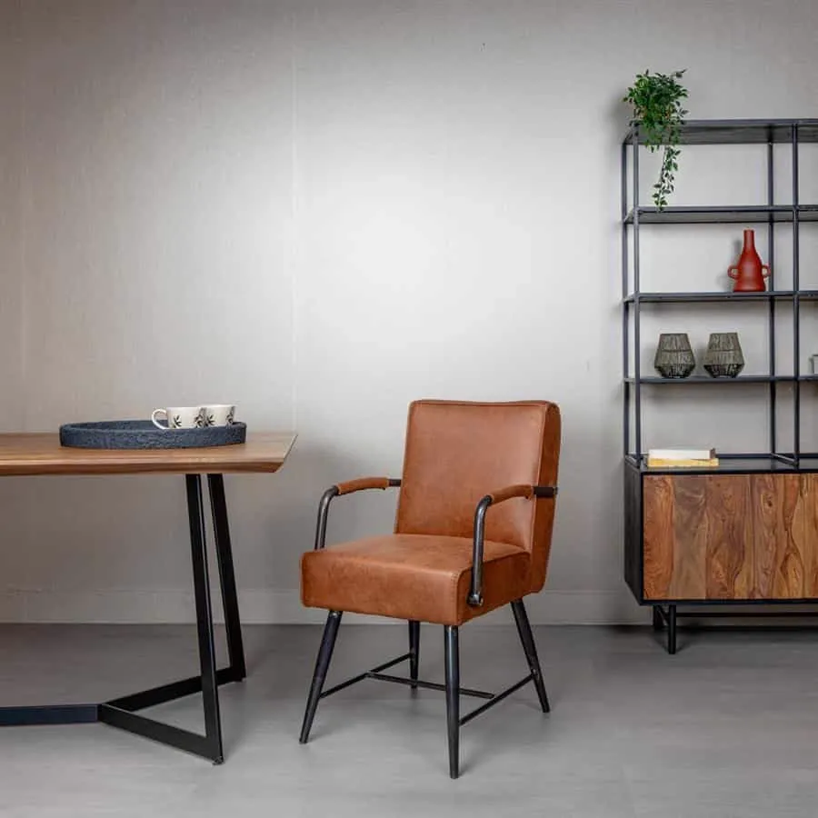 Belmonte Armstoel in cognac stof met zwarte poten, staand in een moderne woonkamer naast een houten tafel - Tower Living
