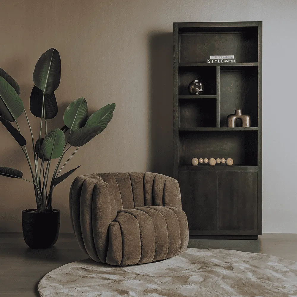Drehsessel Verdi in einem stimmungsvollen Wohnzimmer mit großer Pflanze und dunklem Bücherregal - Tower Living