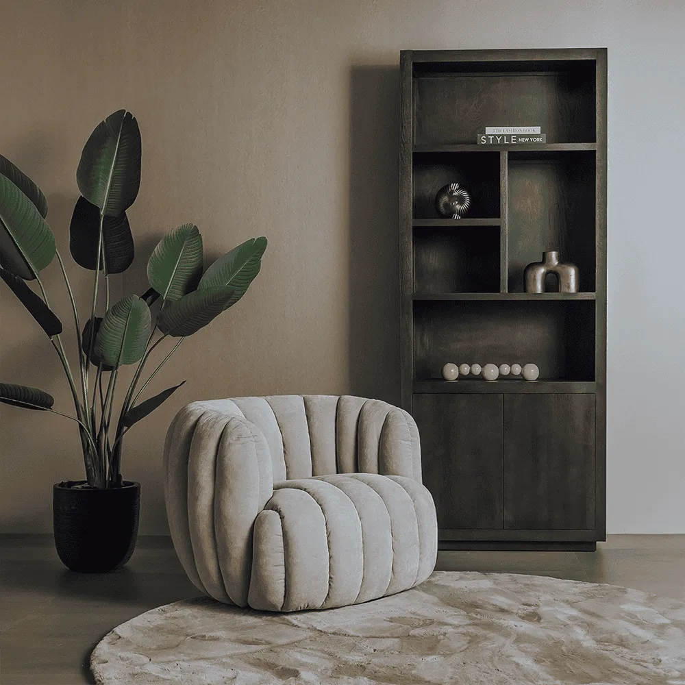 Drehsessel Verdi in einem stimmungsvollen Wohnzimmer mit großer Pflanze und dunklem Bücherregal - Tower Living